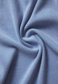Tecido azul claro com uma textura canelada, dobrado para revelar a sua qualidade macia e elástica e a cor consistente em toda a extensão.