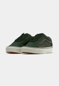 Green suede sneakers with black accents, round toe, white rubber sole, and textured upper. Features laces and side stripe detail.