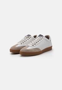 Hvite lær sneakers med grå semsket skinn detaljer, flate snørebånd, gummisåler og perforert detaljering på overflaten.