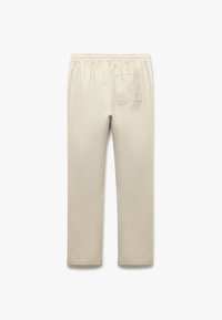 Beige puuvillasegu püksid, millel on elastne vöökoht, sirged sääred ja üks tagatasku. Pehme tekstuur ja minimaalne disain.