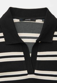 Schwarz-beiges, gestreiftes Poloshirt mit einem Kragen, das ein knopflose V-Ausschnitt-Design und einen weichen, strukturierten Stoff aufweist.