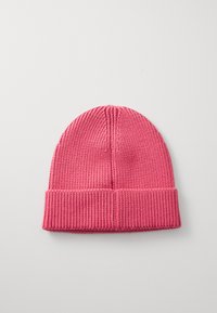 Pletená růžová čepice s ohnutým ribbed manžetou. Hladká textura s vertikálním pruhovaným vzorem po celém těle.