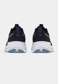 Tengerészkék futócipő texturált hálós felsőrésszel, fehér középtalppal és kék talppal. Sárga díszítésekkel és sarkán húzófüllel rendelkezik.
