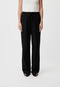 Pantaloni da jogging neri, comodi e larghi, con vita regolabile tramite coulisse. Tessuto liscio con design a gamba dritta, senza modelli o dettagli visibili.