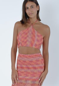 Top corto con scollatura a halter multicolore con motivo a zigzag nelle tonalità di arancione e rosa, abbinato a una gonna aderente coordinata, entrambi realizzati in tessuto morbido.