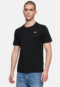 T-shirt in cotone nero con collo rotondo, maniche corte e un piccolo logo FILA bianco e rosso sul petto. Tessuto morbido e design aderente.