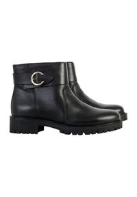 Botas de cuero negro hasta el tobillo con un puño ancho que presenta un acento circular dorado. Suela de goma gruesa con un diseño de banda de rodadura.