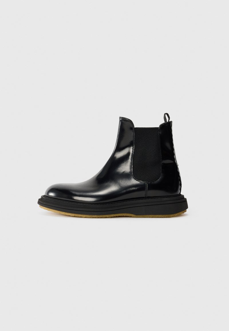 Black leather Chelsea boot with a shiny finish, elastic side panels, pull tab, and a textured rubber sole.