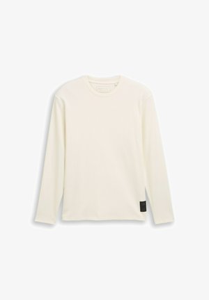 Long-sleeve, cream-colored T-shirt made of ribbed fabric. Features a round neckline and a small black label accent on the side.