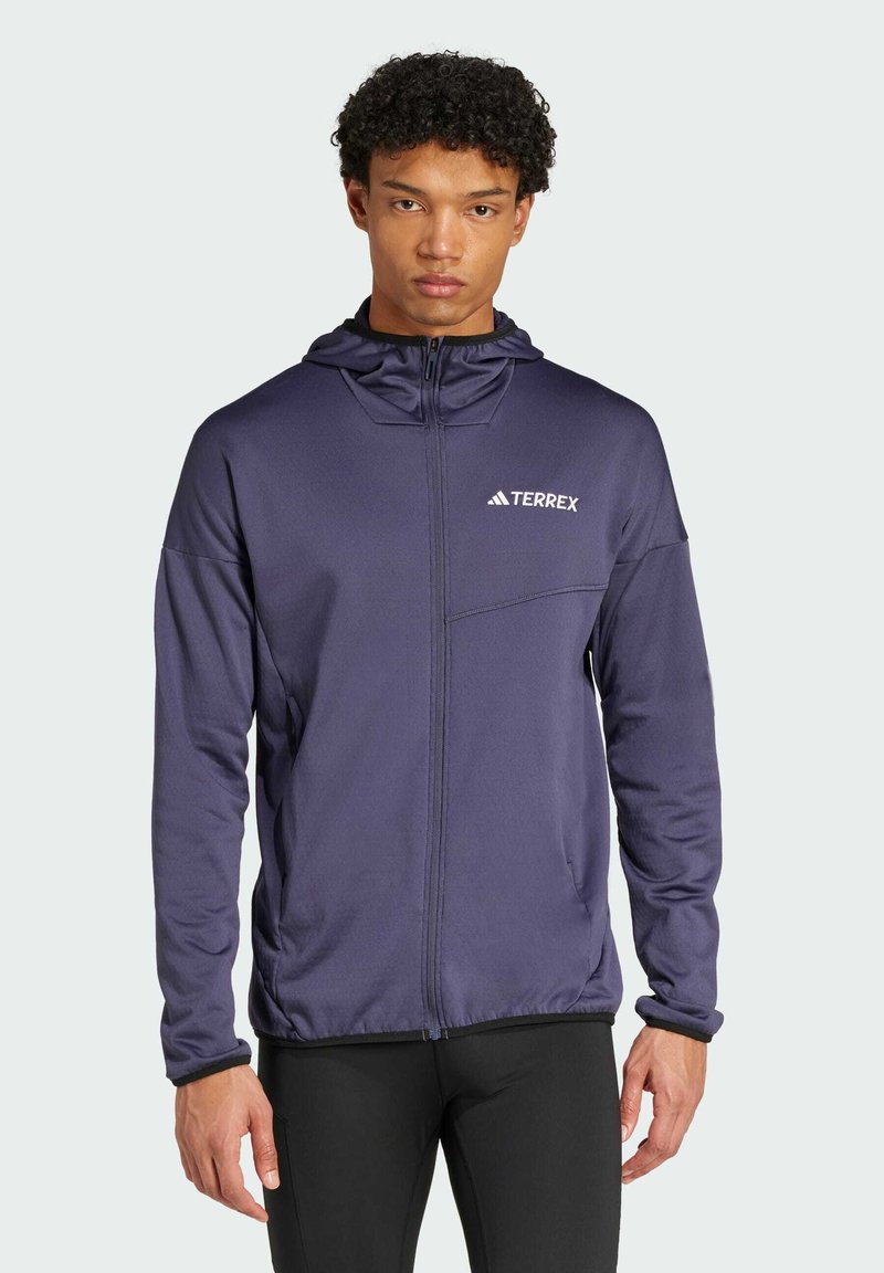 Veste à capuche bleue marine avec zip complet, marquée "TERREX" sur la poitrine, dotée d'une poche avant et d'un tissu texturé pour plus de chaleur.