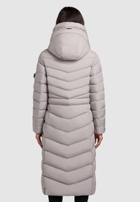 Manteau matelassé long gris clair avec un motif en chevrons et une capuche. Le manteau présente un quilting horizontal et des poches latérales.