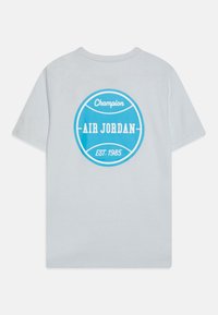 Jasnoszara bawełniana koszulka z dużą niebieską okrągłą grafiką z napisem "Champion", "AIR JORDAN" oraz "EST. 1985" na plecach.