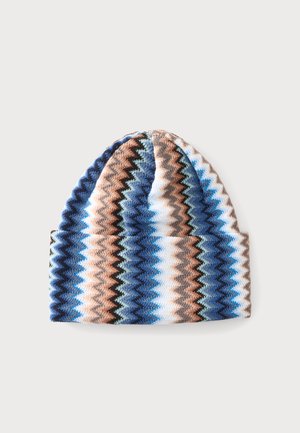 Knit beanie with zigzag stripes in blue, brown, white, and black colors on a light background.