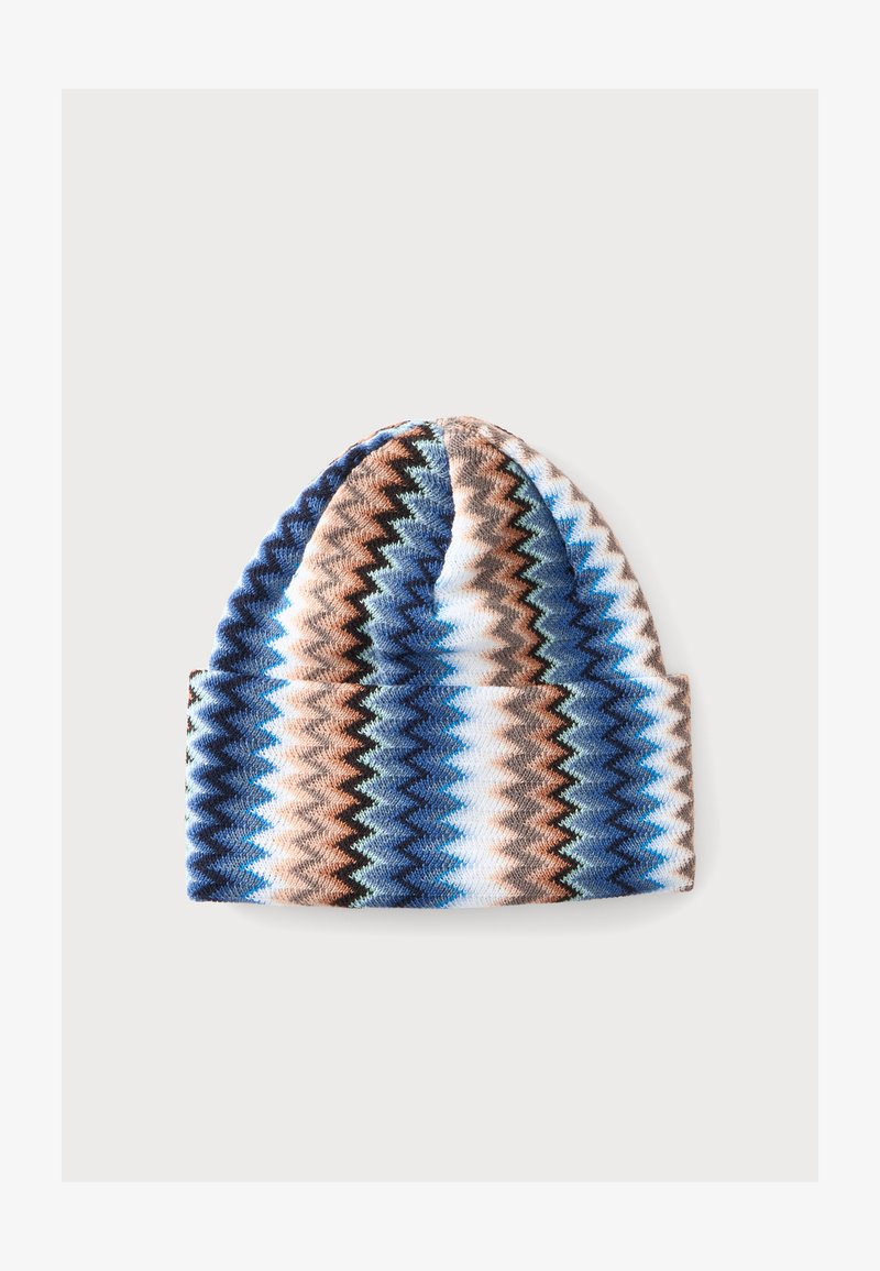 Bonnet tricoté avec des rayures en zigzag bleu, marron, blanc et noir sur un fond clair.