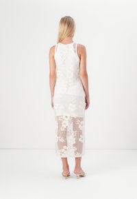 Bela čipkasta obleka z rožnatimi vzorci, polprosojen material, obleka do kolen z oprijetim zgornjim delom in razširjenim robom.