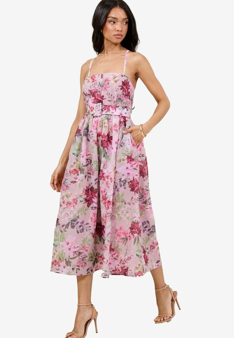 Abito midi floreale in tonalità di rosa, con un corpetto aderente, spalline sottili, vita cinturata e tasche laterali. Realizzato in tessuto leggero.