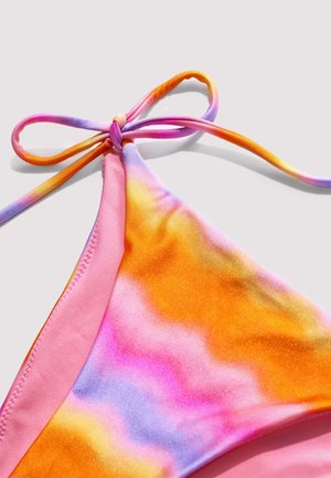 Bas de bikini tie-dye aux teintes orange, rose et violet avec un lien latéral ajustable sur un fond clair.
