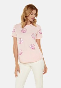 Lyserød kortærmet t-shirt med skinnende lyserøde muslingemotiver. Blødt stof med en afslappet pasform og rund halsdesign.
