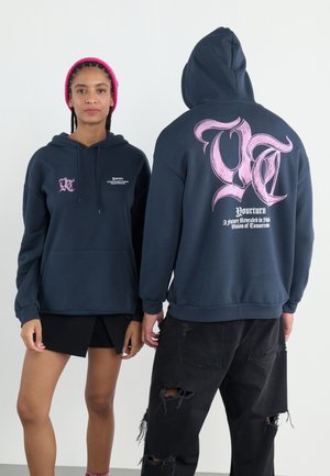 Navy hooded sweatshirt with a front pocket, featuring a pink graphic logo on the back, and printed text. The fabric looks soft and textured.