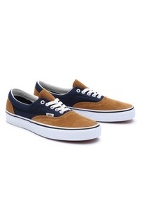 Brune og marineblå Vans-sneakers laget av kordfløyel og stoff, med hvite lisser, en hvit såle og en svart detalj rundt sålekanten.