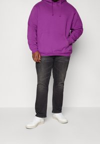 Violetti huppari kengurutaskulla, kiristysnauhalla varustettu hupulla ja pitkillä hihoilla, yhdistettynä tummiin farkkuihin ja valkoisiin tennareihin. Rentoon tyyliin suunniteltu asu.