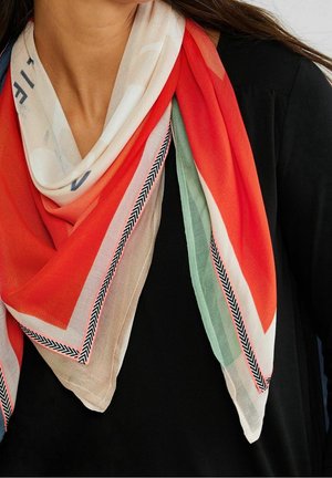 Écharpe légère multicolore avec une bordure en chevrons rouge, vert, beige et noir, portée autour du cou sur un haut noir.