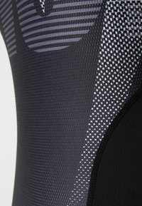 Μαύρο αθλητικό ύφασμα με υφή που περιλαμβάνει οριζόντιες ρίγες και καρό σχέδιο, με έμφαση σε ραφή για επιπλέον δομή.