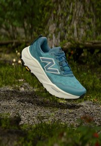 Türkiissinine jooksujalanõu võrgust pealsega, valge "N" logoga ja musta kummist tallaga. Märgatav "FRESH FOAM" brändimine vahetallal.