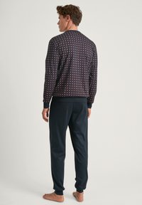Heren pyjama set met een marineblauw gestreept langemouwen shirt met een ribgebreide manchette en bijpassende marineblauwe broek met taps toelopende pijpen en enkelmanchetten.