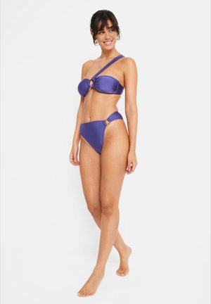 Lilla bikini-sett med en skulder bandeau topp som har en sirkulær aksent, og matchende høytlivsbukser med side ringer. Glatt tekstur.