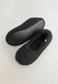 Black felt slippers with a rounded toe, soft texture, and a rubber sole featuring a textured pattern for grip.