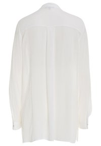 Camicia bianca a maniche lunghe con tessuto texturizzato. Presenta uno yoke posteriore, un orlo arrotondato e polsini con bottoni. Design minimalista.