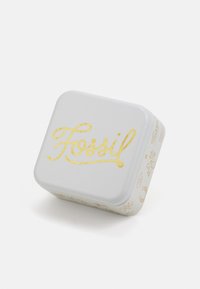 Cutie metalică gri cu colțuri rotunjite, având un logo „Fossil” aurit și accente decorative aurii. Textură netedă și formă pătrată compactă.