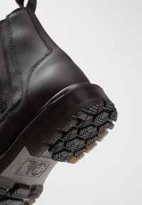 Sorte lær ankle boot med en teksturert overflate, som har en kraftig gummisåle og dype mønstre for godt grep.