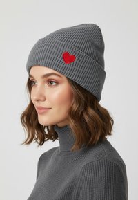 Gray ribbed knit beanie featuring a small red heart embroidery on the front, paired with a matching gray turtleneck sweater.