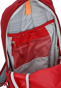 Interior de mochila roja con forro gris. Cuenta con un bolsillo de malla y una etiqueta de tirón naranja cerca de la cremallera. Tela suave y diseño estructurado.