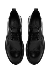 Zwarte leren schoenen met een wingtip-design, gestructureerd oppervlak en veters. Voorzien van een trekband aan de hiel en een gestructureerde rubberen zool.