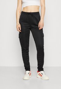 Svarta cargojoggers med dragsko i midjan, sidofickor och elastiska muddar. Tillverkade av ett mjukt tyg, utformade för komfort och funktion.