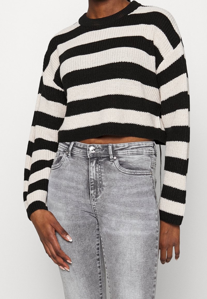 Černobílý pruhovaný krátký pletený svetr s kulatým výstřihem. Kombinováno se šedými džínami z denimu, klasického střihu a s mírně vypranou texturou.