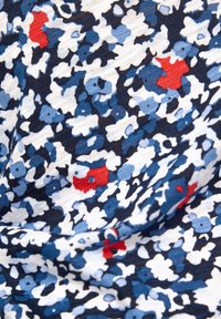 Textil mit einem floralen Muster in Marineblau, Weiß und Blau, mit roten Akzenten. Das Material wirkt weich mit einem strukturierten, fließenden Design.