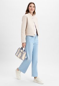 Crème gewatteerde jas, lichtkleurige denim wijde jeans en een kleine gestreepte handtas in crème en blauw. Witte sneakers maken de outfit compleet.