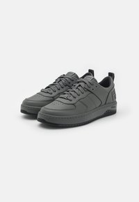 Gray sneakers made of smooth leather, featuring a low-top design, round toe, flat rubber sole, and subtle branding on the tongue and heel.