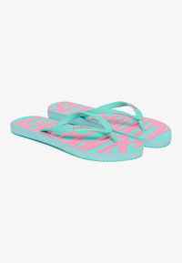 Flip flops i turkis og pink gummi med et iøjnefaldende mønster, der har ordet "SUPERDRY." Tynde, strukturerede stropper med en flad sål.