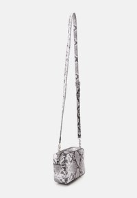 Obdélníková crossbody taška s černobílým hadím vzorem, hladkým povrchem, nastavitelným popruhem a stříbrnými kovovými detaily.