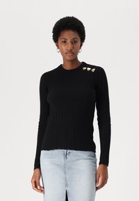 Sort ribbet sweater med lange ærmer, rund halsudskæring og tre guldhjerte-formede detaljer på venstre skulder. Tekstureret stof.