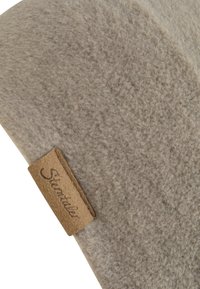 Close-up of beige fleece fabric with a small brown leather tag stitched on, displaying the brand name "Sterntaler" in cursive.