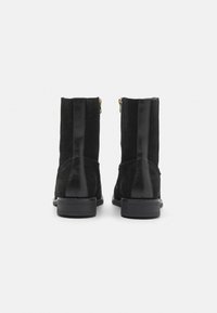 Bottines noires en suède et cuir. Détails zippés et semelle en caoutchouc plate. Design simple et structuré.
