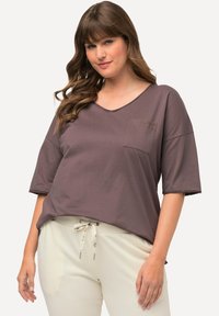 Brun, kortærmet V-hals t-shirt med en lomme. Har "LOVE" broderi på lommen. Blødt stof med en afslappet pasform.