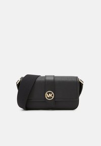 Bolso bandolera de piel negra con un logo dorado de MK, que cuenta con un cierre tipo solapa, superficie texturizada y una correa de tela. Diseño compacto y rectangular.