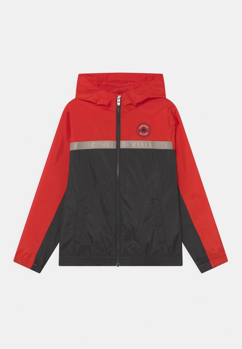 Rød og sort vindjakke med hætte, front lynlås, to sidelommer og en lys grå stribe med teksten "CONVERSE ALL STAR".